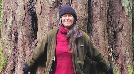 Person hugging a large tree outside Amorah Rose Intuitive, Whakatane, Bay Of Plenty, NZ