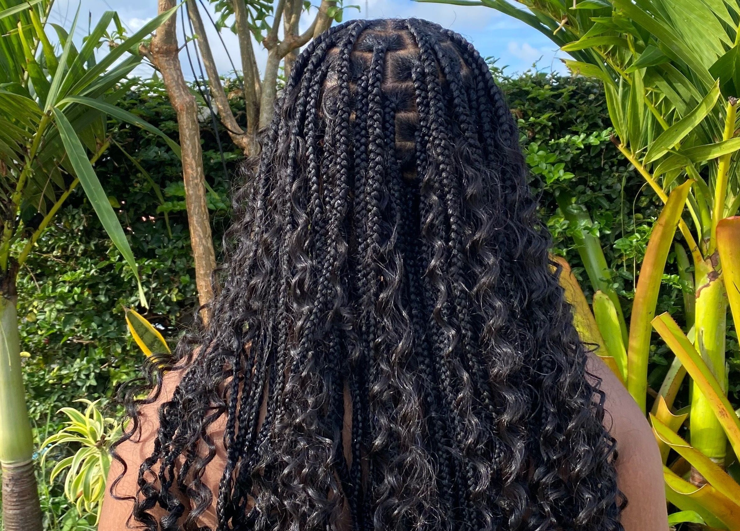 Braided hairstyle showcased at Flux Beauty, Oistins, Christ Church, BB with lush greenery in the background.