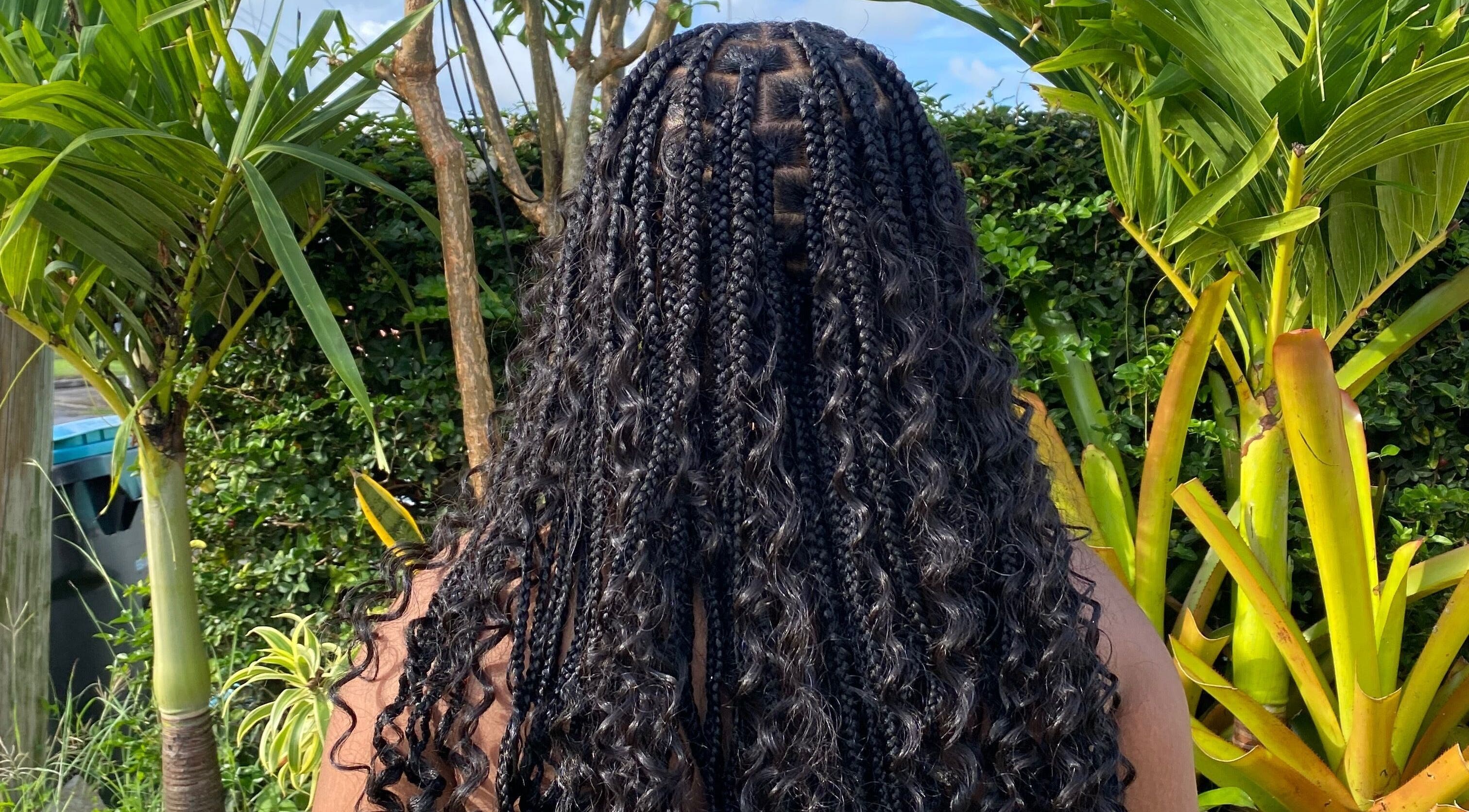 Braided hairstyle showcased at Flux Beauty, Oistins, Christ Church, BB with lush greenery in the background.