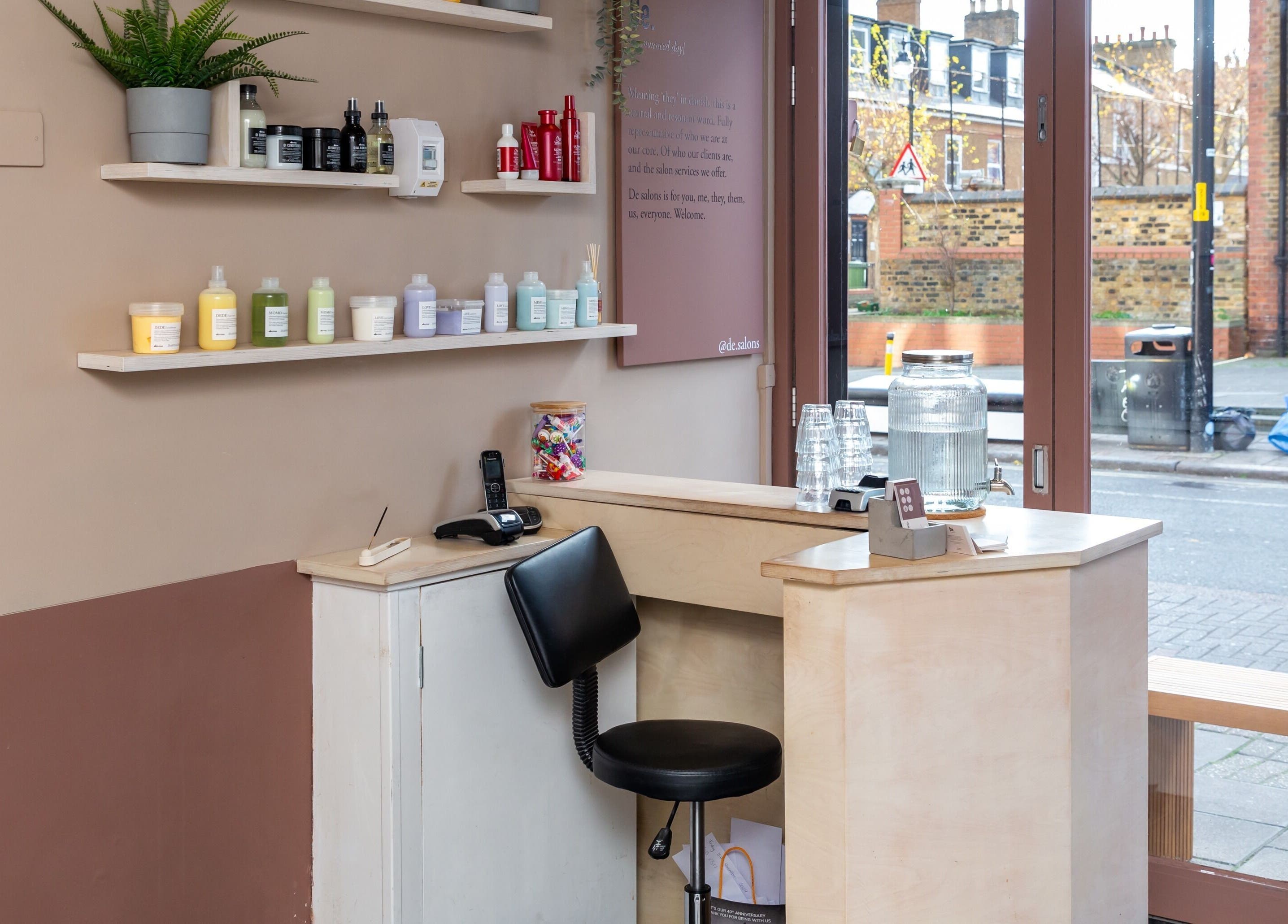 Reception desk with beauty products at De.Salons Peckham, London, England, GB, showcasing a modern, inviting space.