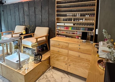 Rincón acogedor en Hi Hi Nails Roma, Ciudad De México, MX, con sillas confortables y esmaltes exhibidos.