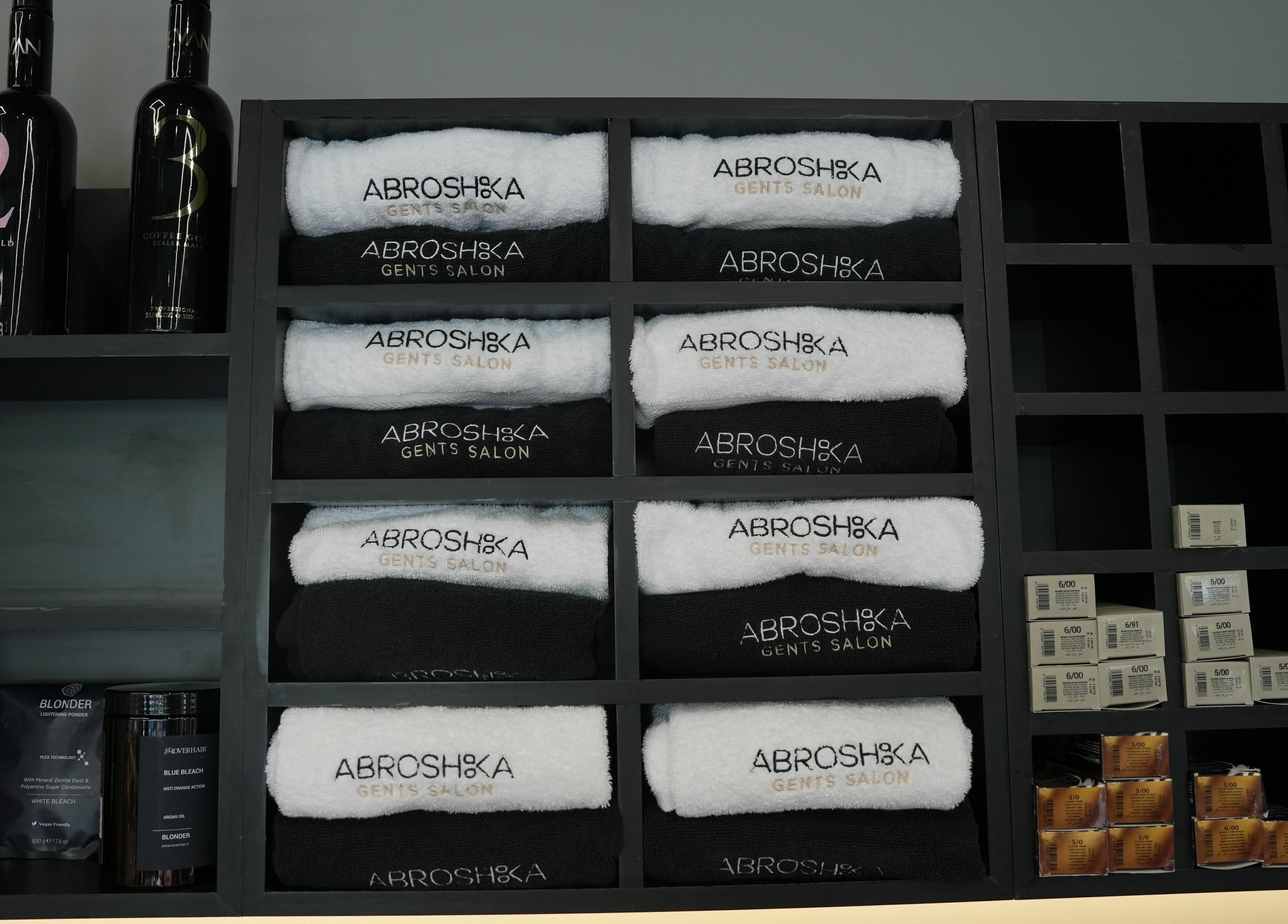Abroshka Gents Salon shelves with branded towels and products in Dubai, AE, neatly organized.
