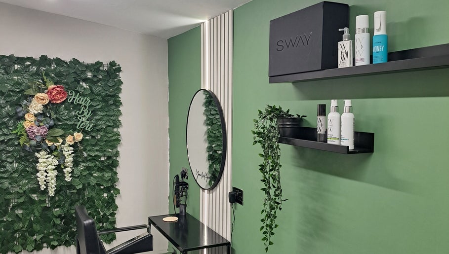 Elegant salon setup at Hair by Teri, Wishaw, Scotland, GB with lush greenery and stylish shelves.
