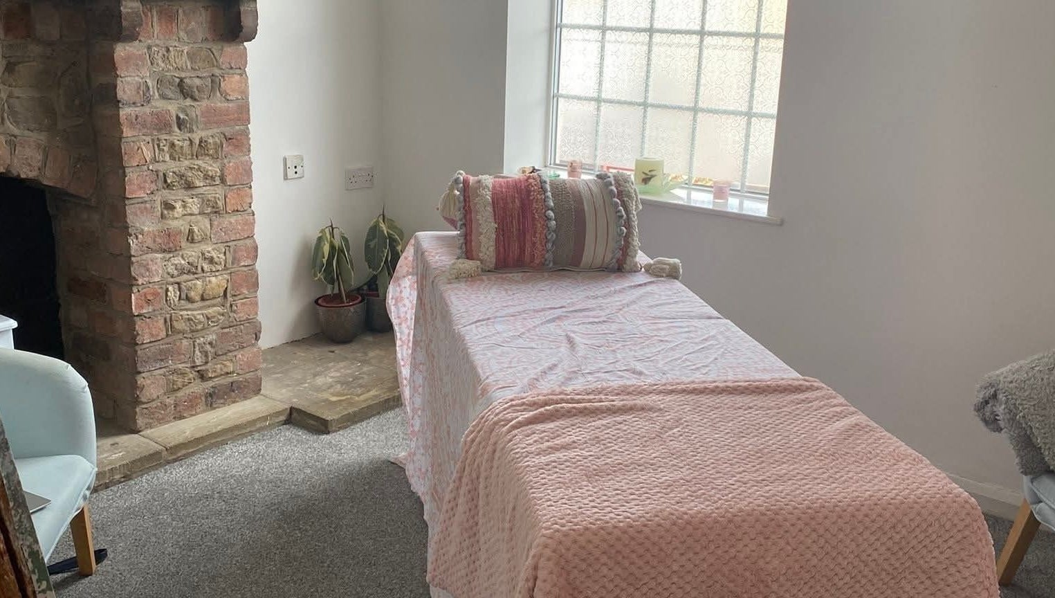 Cozy treatment room at Skin&soul by Siena, Northampton, England, GB with a pink blanket and rustic fireplace.