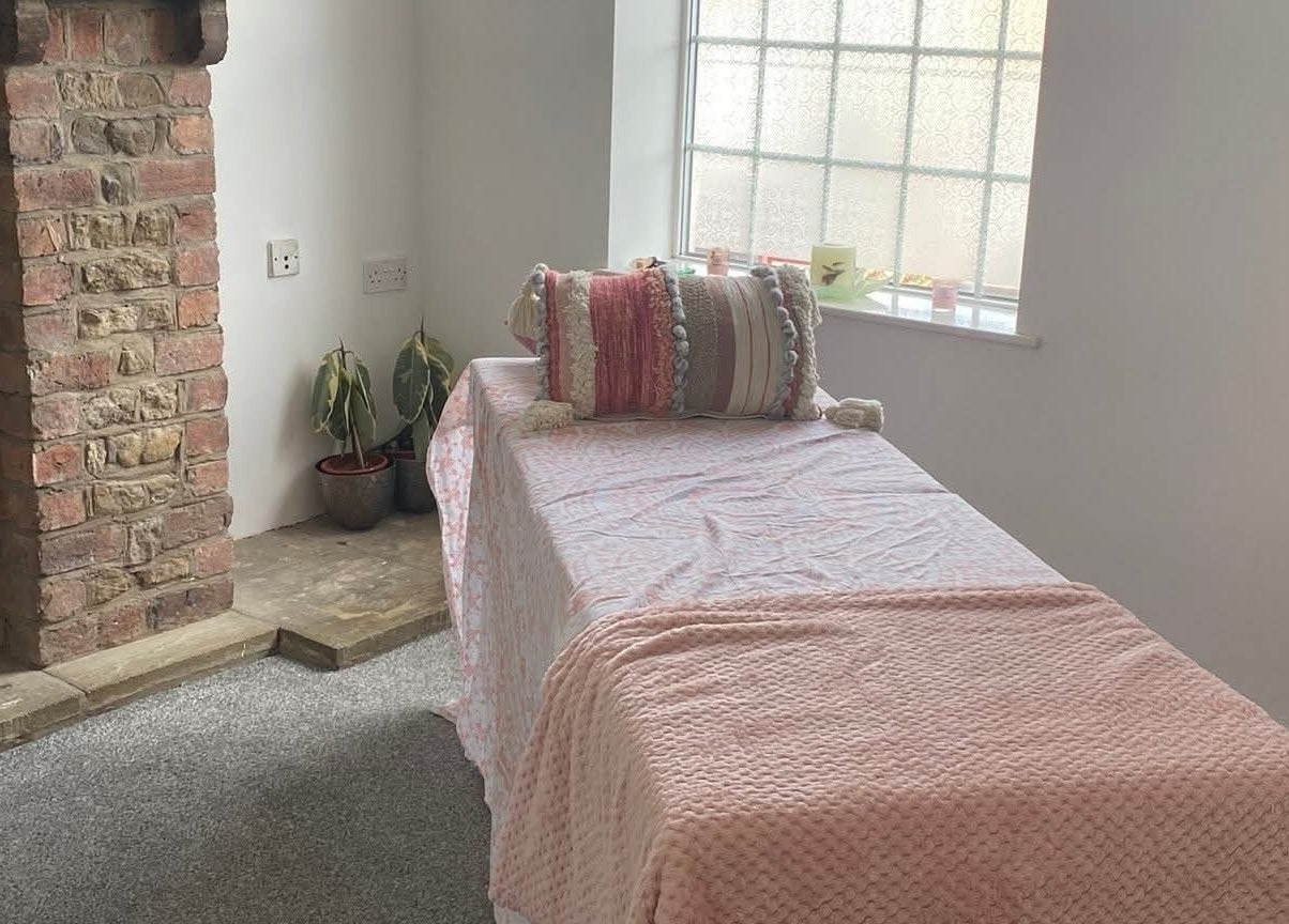 Cozy treatment room at Skin&soul by Siena, Northampton, England, GB with a pink blanket and rustic fireplace.