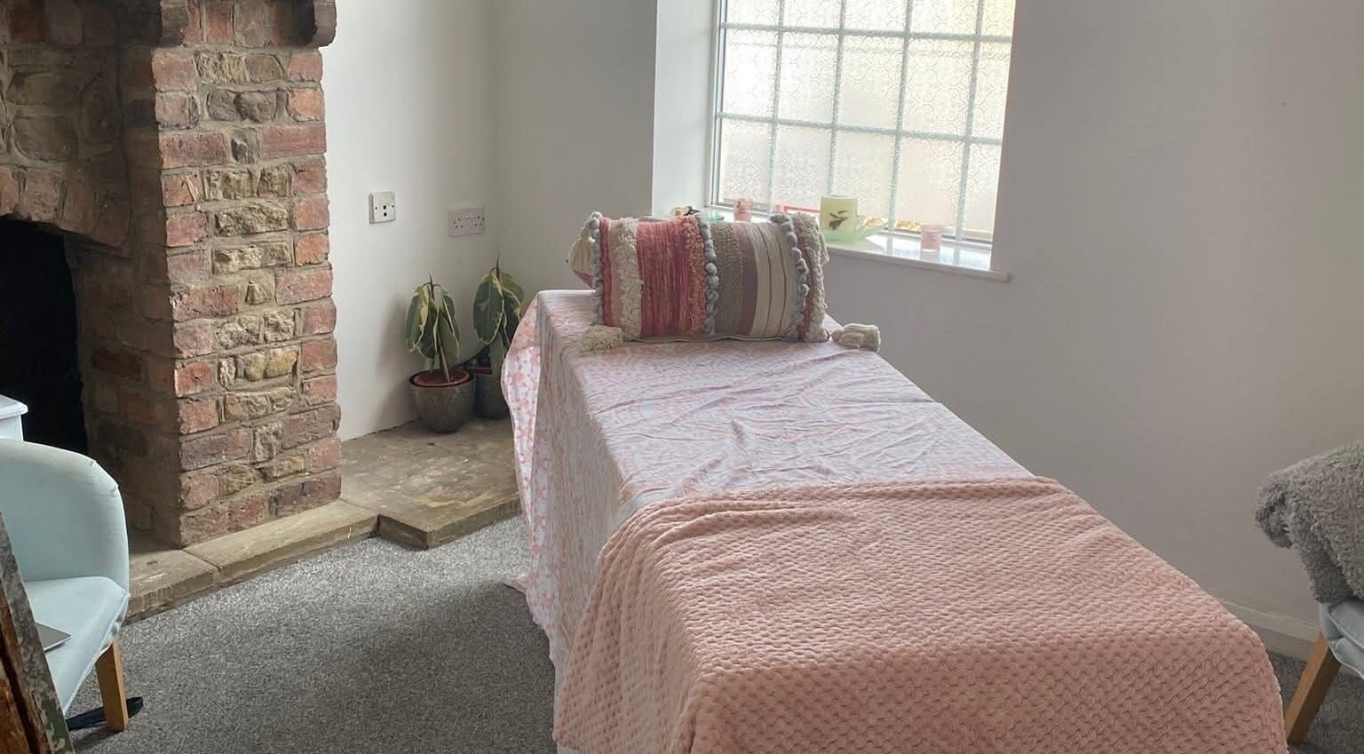 Cozy treatment room at Skin&soul by Siena, Northampton, England, GB with a pink blanket and rustic fireplace.
