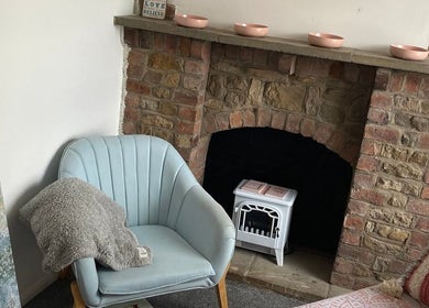Enchanting corner at Skin&soul by Siena, Northampton, England, GB with a plush chair by rustic fireplace.