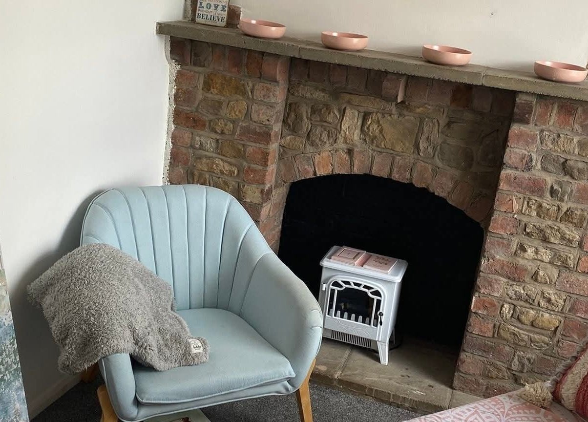 Enchanting corner at Skin&soul by Siena, Northampton, England, GB with a plush chair by rustic fireplace.