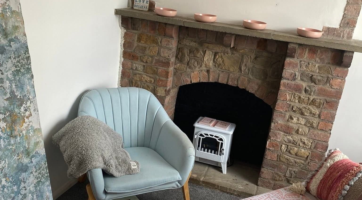 Enchanting corner at Skin&soul by Siena, Northampton, England, GB with a plush chair by rustic fireplace.