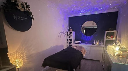 Relaxing spa room at The Rectory Retreat, Rochford, England, GB, featuring cozy lighting and a treatment bed.