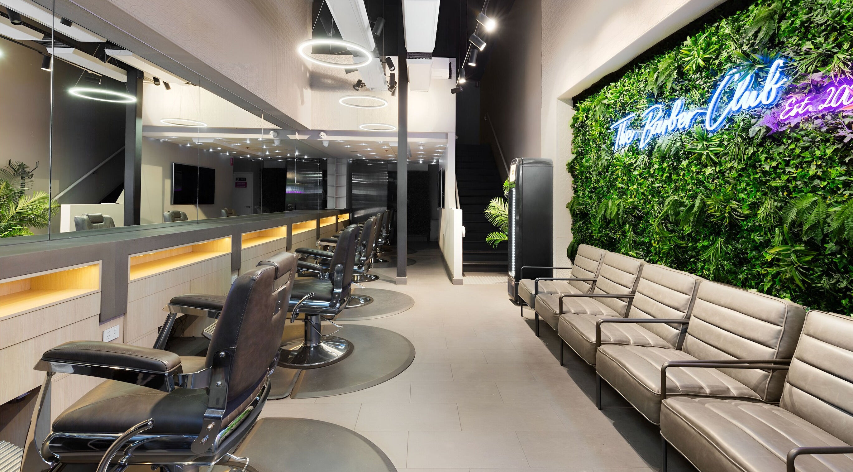 Modern interior of The Barber Club Port Melbourne, Melbourne, Victoria, AU with stylish seating and greenery.