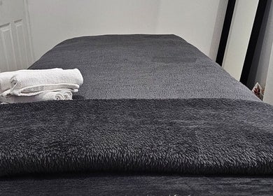 Cozy massage table with gray towels at Hexie Beauty in Manchester, England, GB, perfect for relaxation.