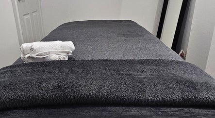 Cozy massage table with gray towels at Hexie Beauty in Manchester, England, GB, perfect for relaxation.