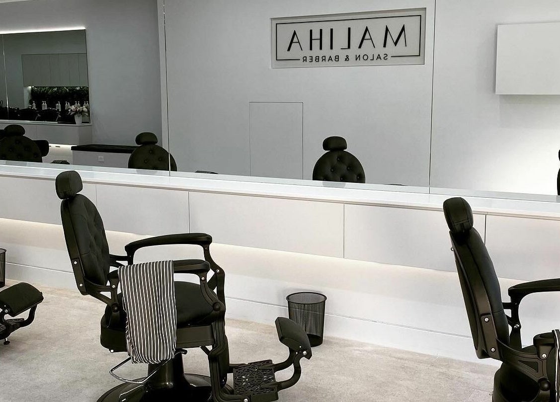 Sleek interior at Maliha Salon And Barber in Melbourne, Victoria, AU with stylish black chairs and large mirrors.