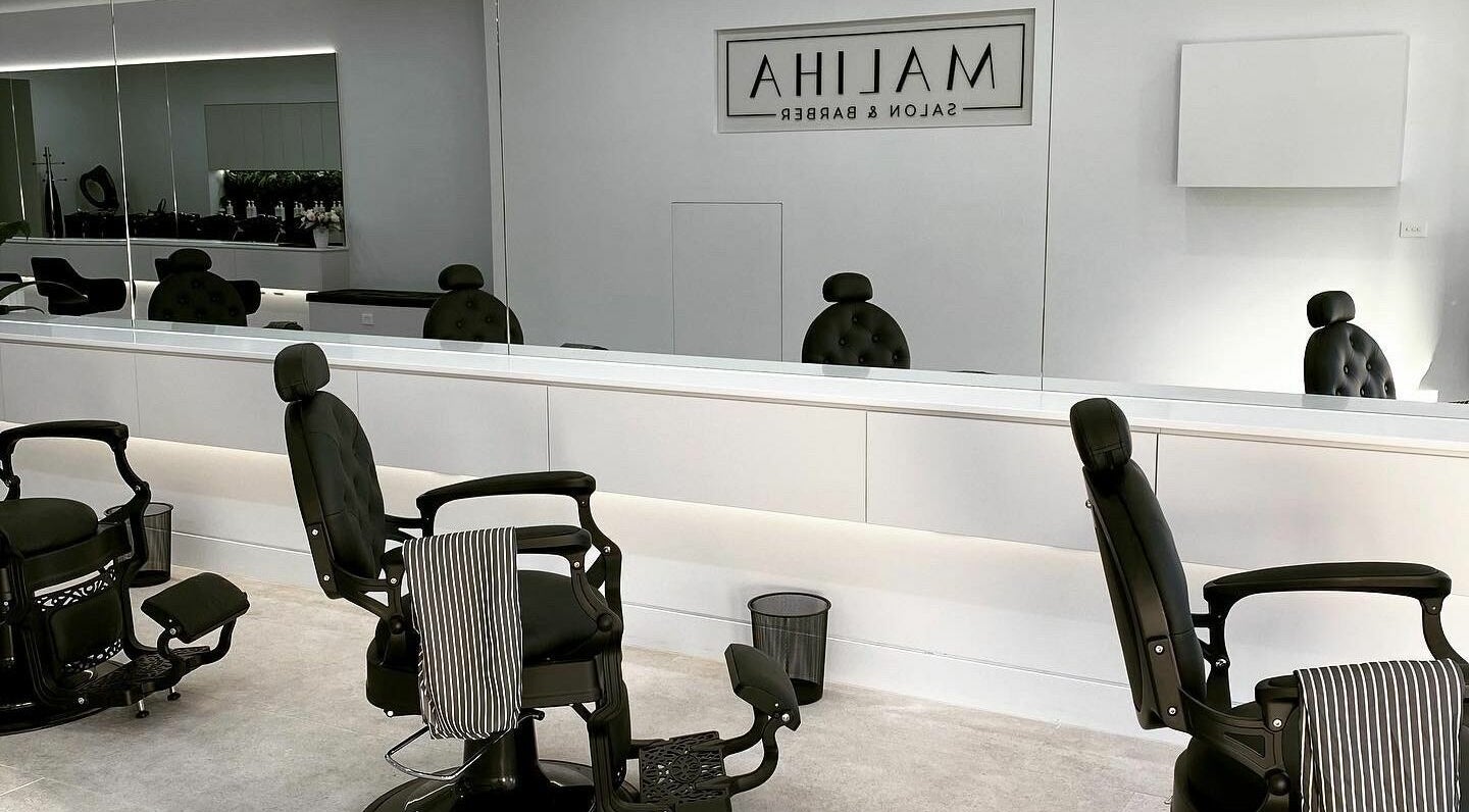 Sleek interior at Maliha Salon And Barber in Melbourne, Victoria, AU with stylish black chairs and large mirrors.