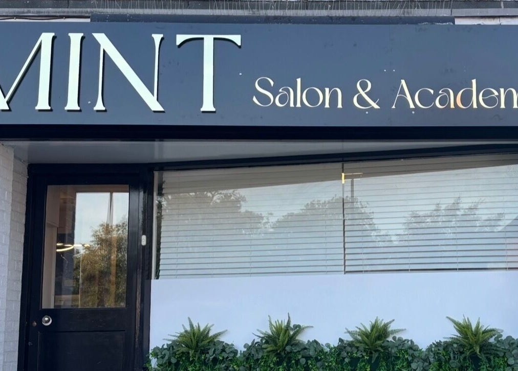 Front view of Mint Salon & Academy, Derby, England, GB, showcasing sleek modern signage and window decor.