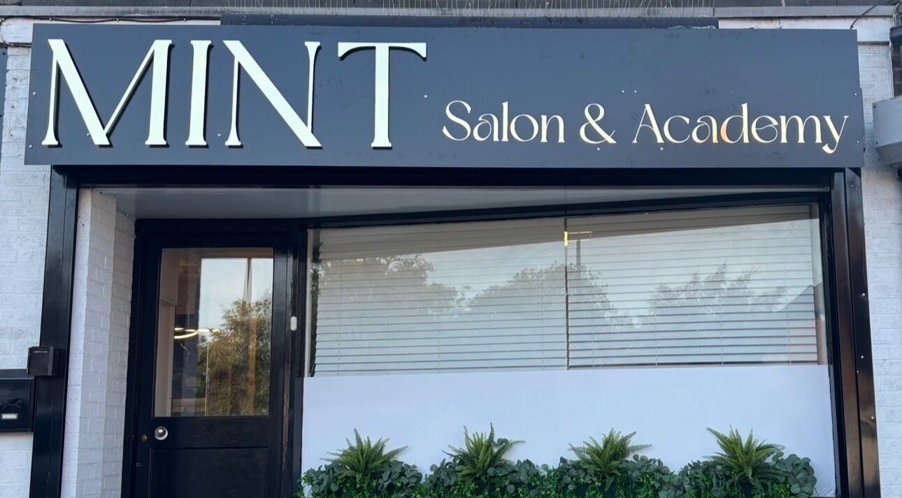 Front view of Mint Salon & Academy, Derby, England, GB, showcasing sleek modern signage and window decor.