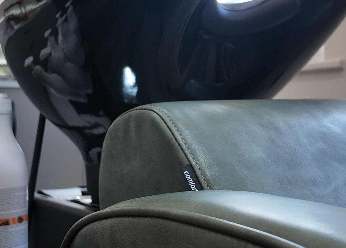 Comfortable wash station chair at Evolved Salon, Boroughbridge, England, GB, with shampoo bottles nearby.