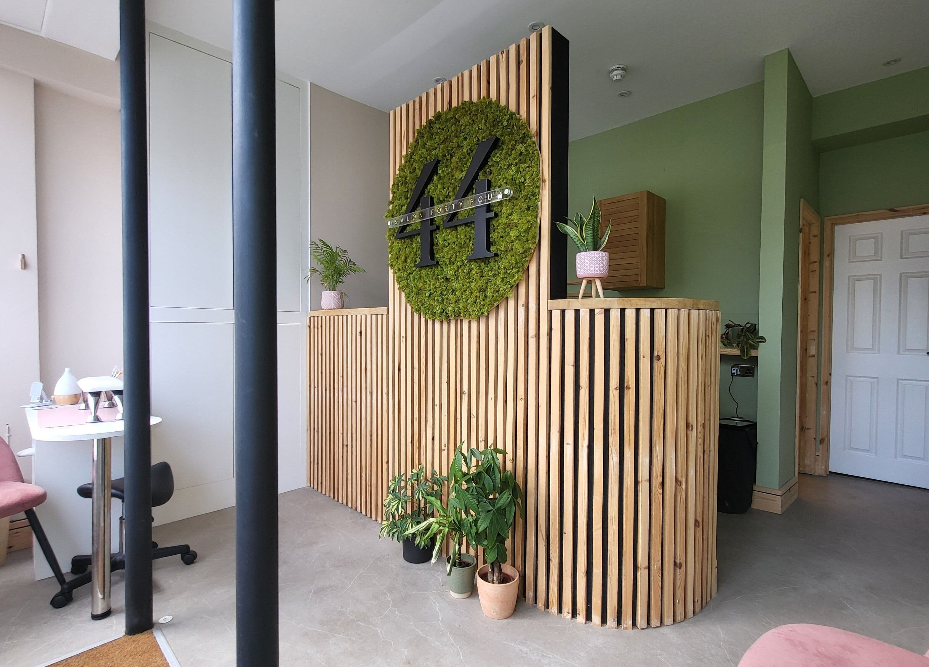 Reception at CK Laser at Salon Forty Four, Eastbourne, England, GB with wood decor and plants.