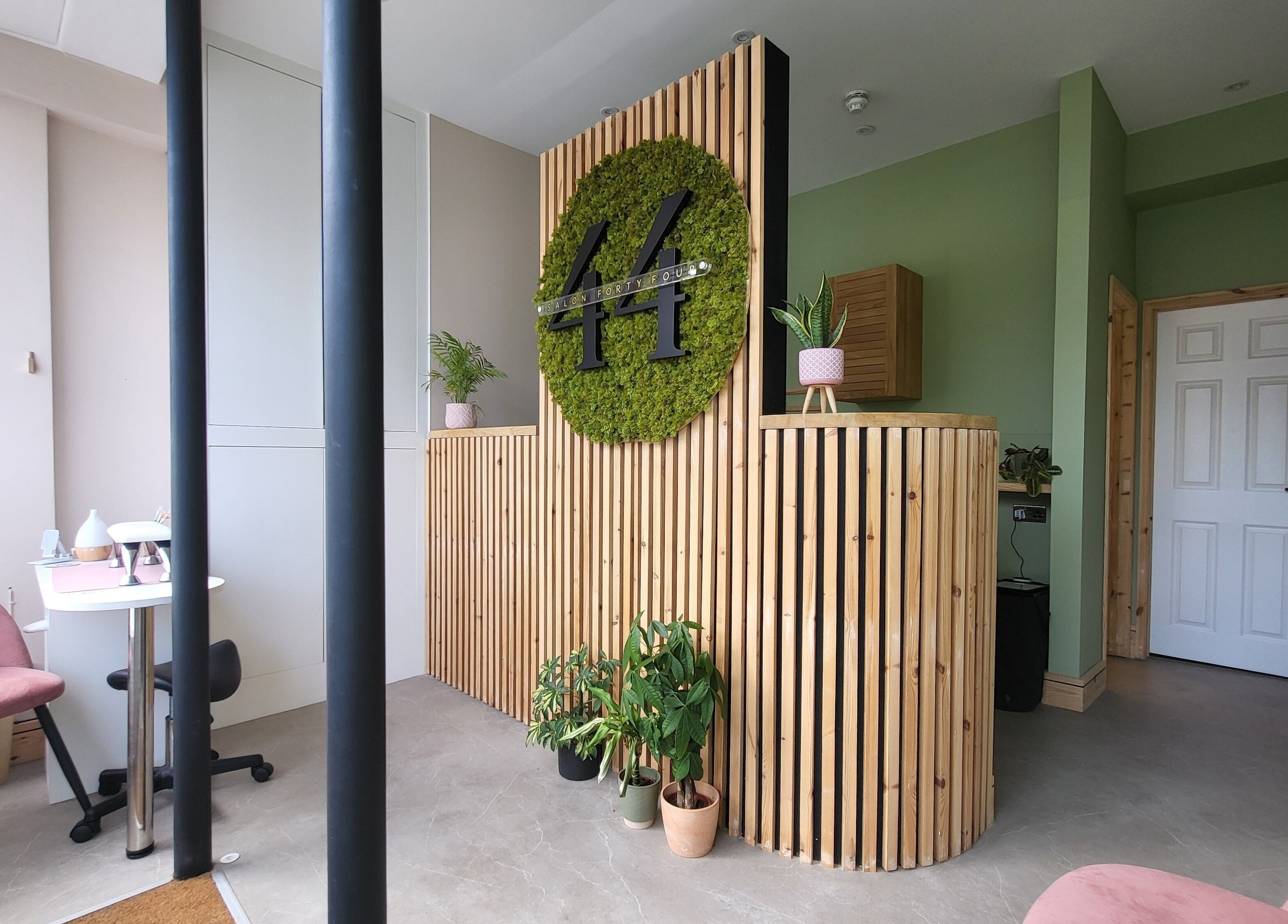 Reception area at CK Laser at Salon Forty Four, Eastbourne, England, GB featuring green decor and wood paneling.
