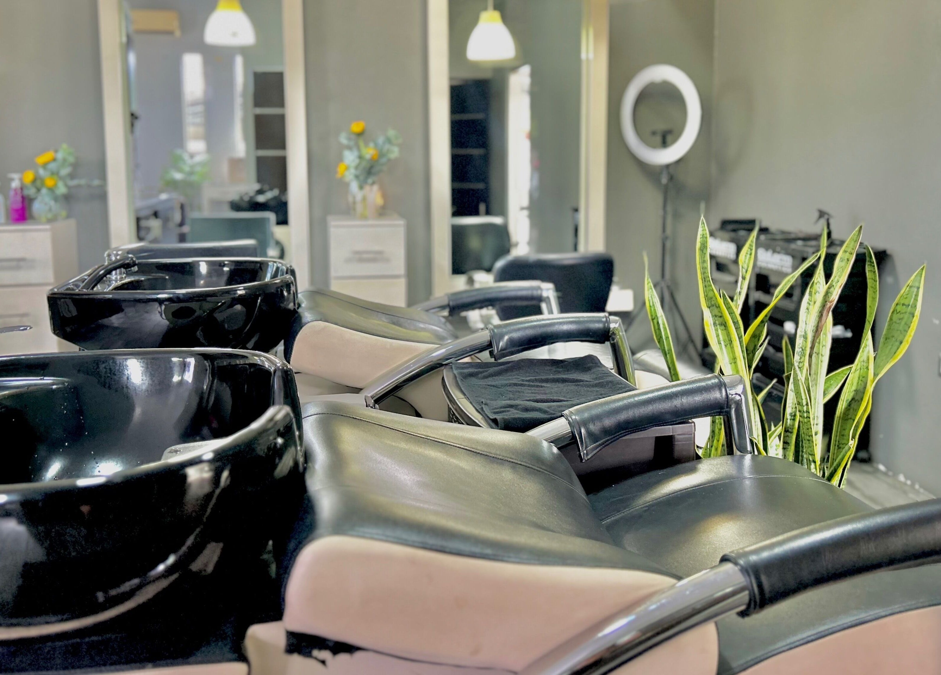 Zona de lavado moderna en Krla Salon, Guápiles, Limón, CR, con sillas cómodas y plantas decorativas.