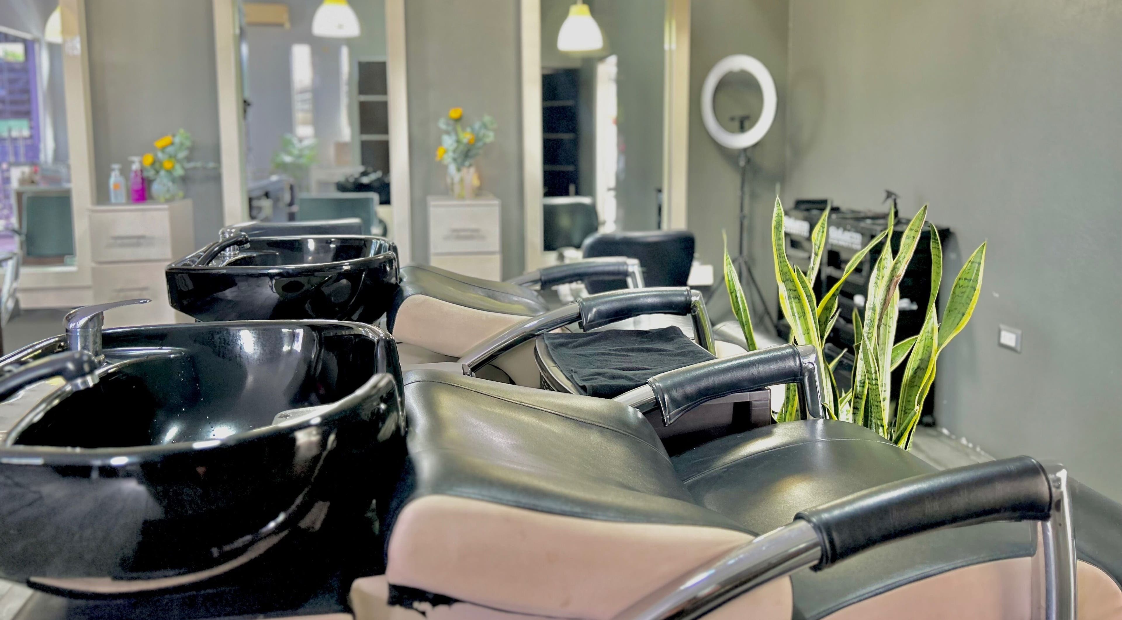 Zona de lavado moderna en Krla Salon, Guápiles, Limón, CR, con sillas cómodas y plantas decorativas.