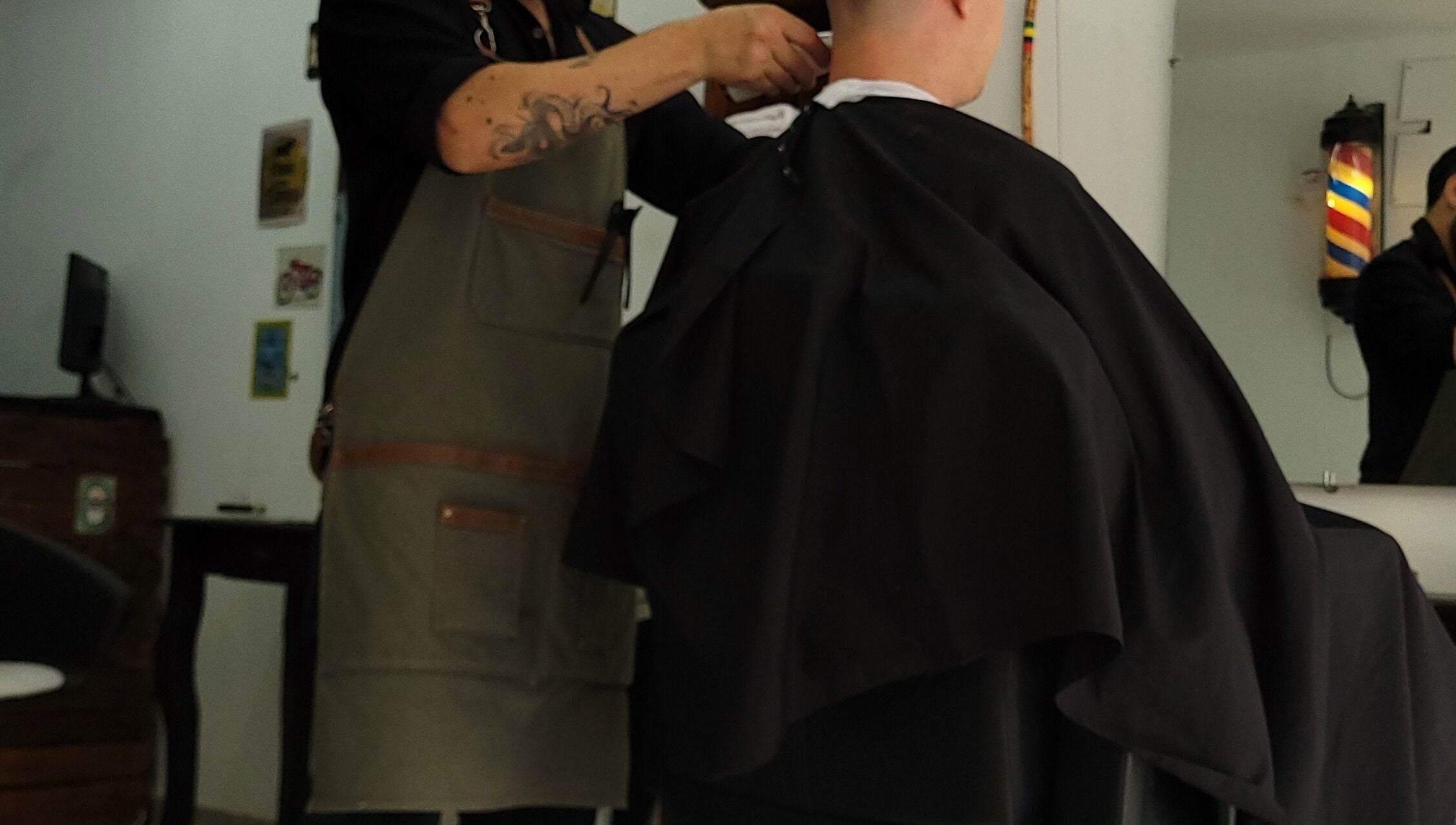 Barbero en Barba Roja ajustando capa a cliente, Córdoba, Córdoba, AR.