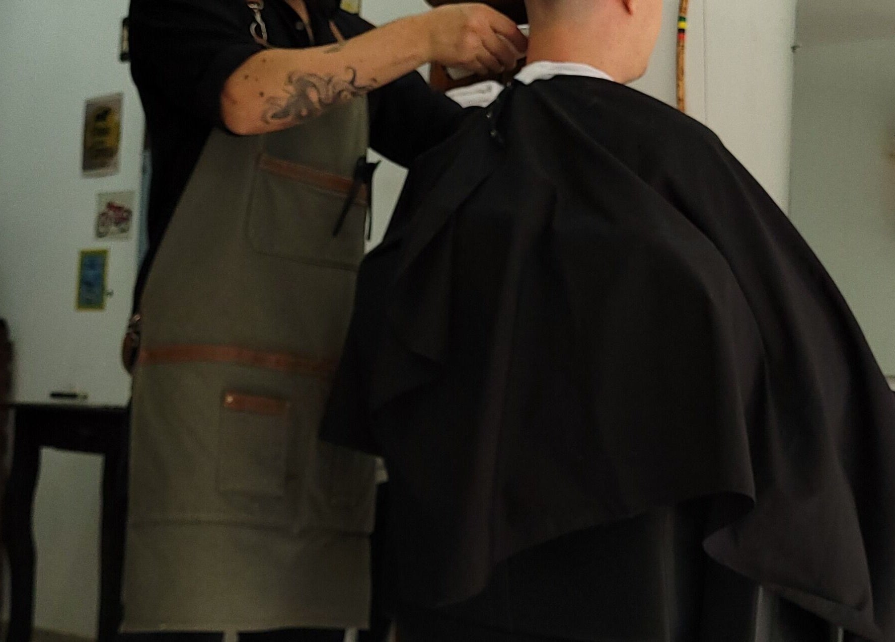 Barbero en Barba Roja ajustando capa a cliente, Córdoba, Córdoba, AR.