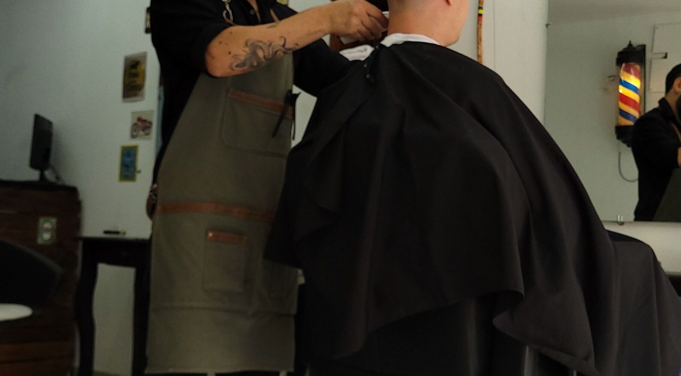 Barbero en Barba Roja ajustando capa a cliente, Córdoba, Córdoba, AR.