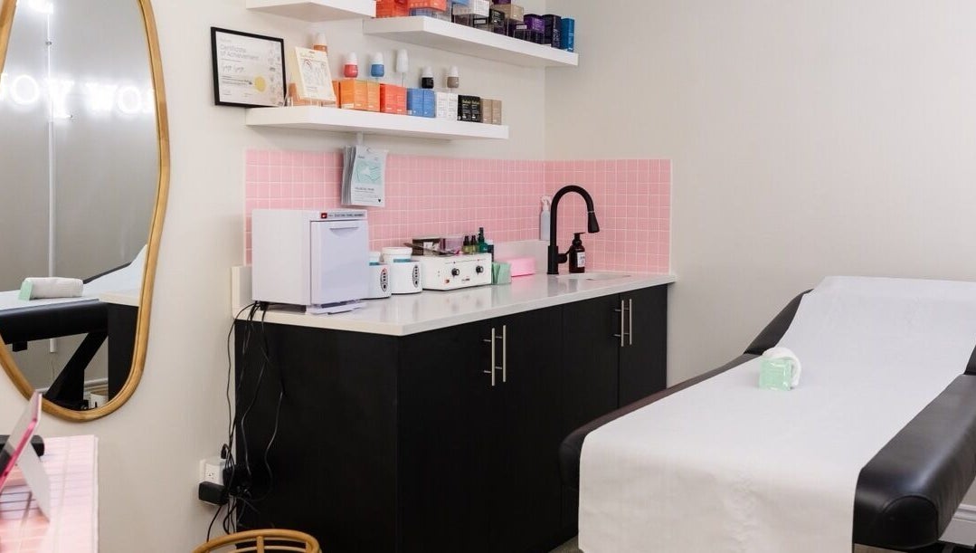 Elegant treatment room at Sugr Sugr Wax Bar, Ottawa, Ontario, CA, featuring black cabinets and a pink tiled wall.