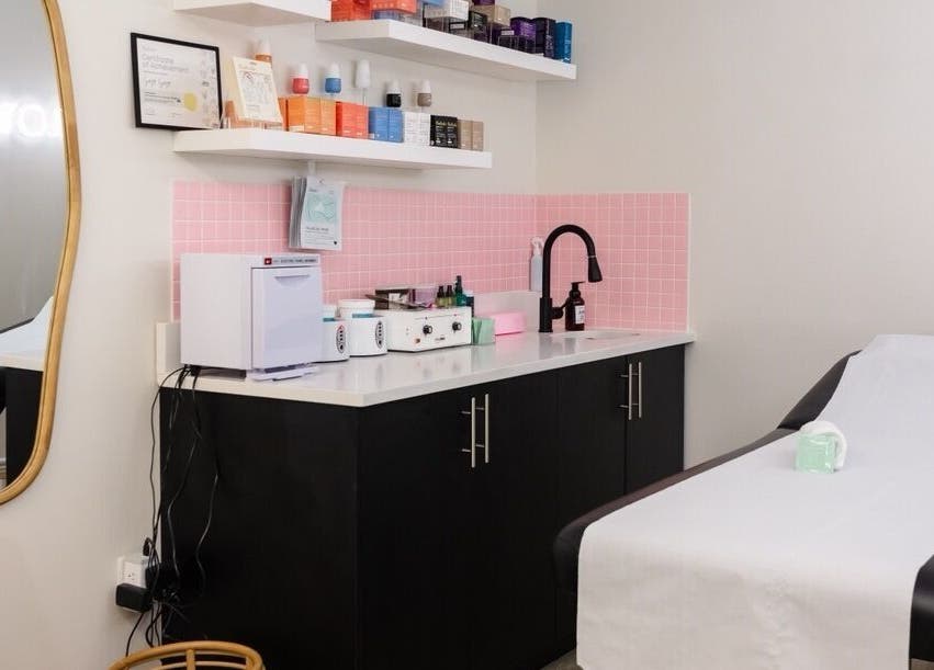 Elegant treatment room at Sugr Sugr Wax Bar, Ottawa, Ontario, CA, featuring black cabinets and a pink tiled wall.
