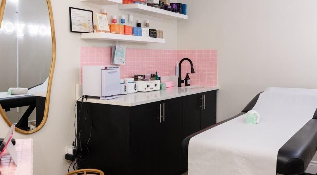 Elegant treatment room at Sugr Sugr Wax Bar, Ottawa, Ontario, CA, featuring black cabinets and a pink tiled wall.