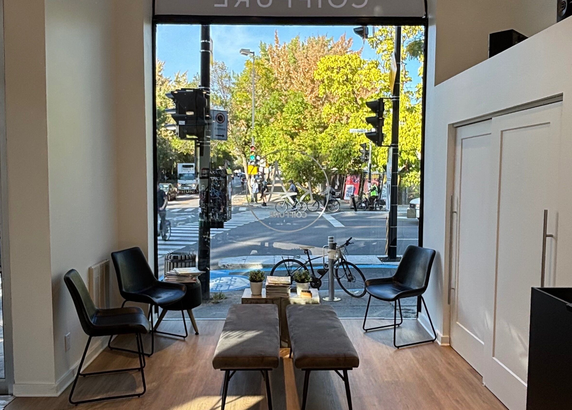 Intérieur paisible de Ka Coiffure à Montréal, Québec, CA, avec grandes fenêtres donnant sur la rue.