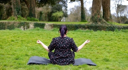 A person meditating in the lush garden of The Green Witches Doneraile Well Being Hub, Doneraile, County Cork, IE.