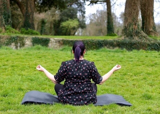 Person meditating in lush greenery at The Green Witches Doneraile Well Being Hub, Doneraile, County Cork, IE.