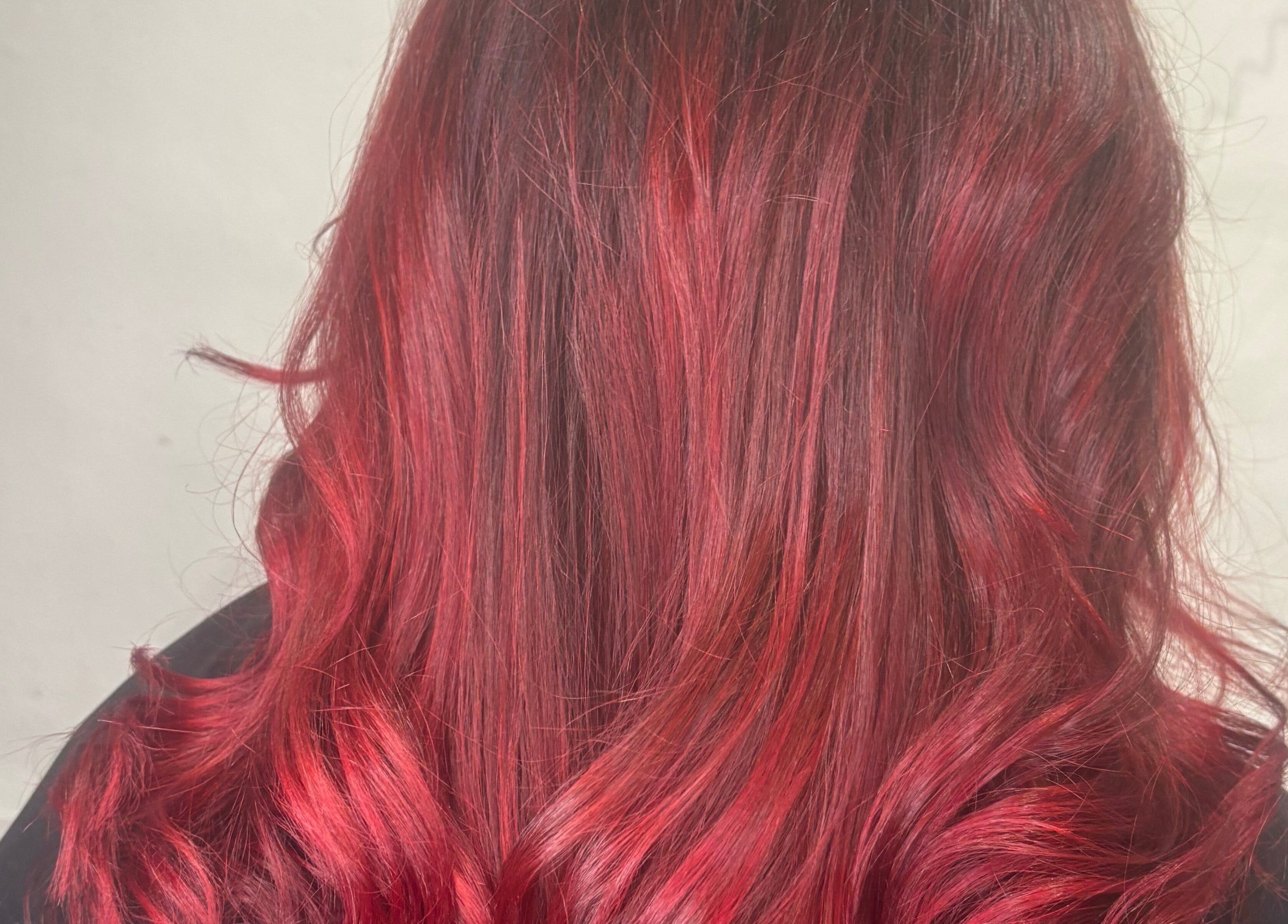 Vibrant red wavy hairstyle at Cove Hair Beauty Wellness in Padstow, England, GB.