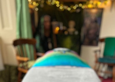 Cozy wellness room at Aura and Earth, Taunton, England, GB, featuring a colorful massage table and chairs.