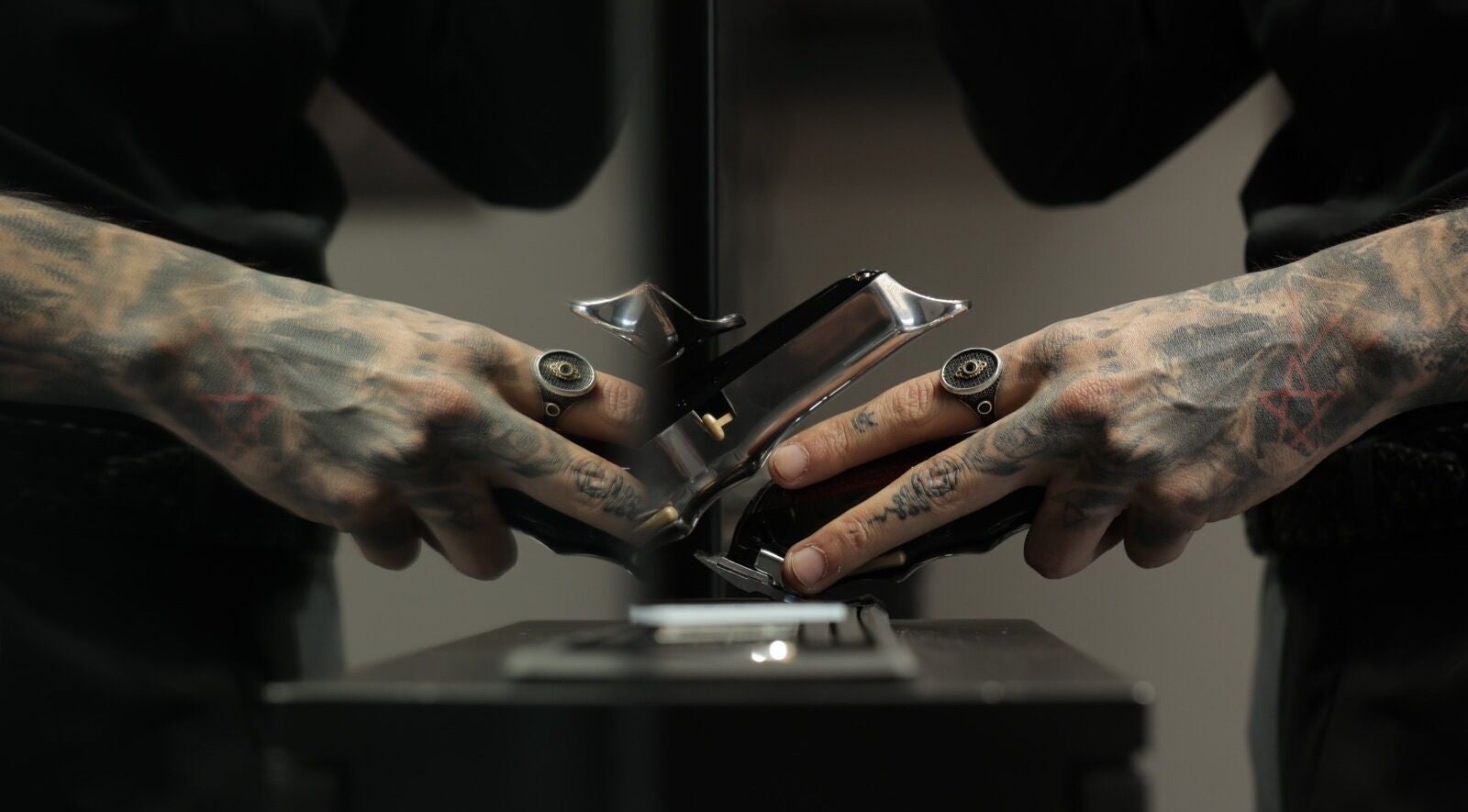 Tattooed hands adjusting clippers at Cutz Hair Studio Premium, Riyadh, Riyadh Province, SA.