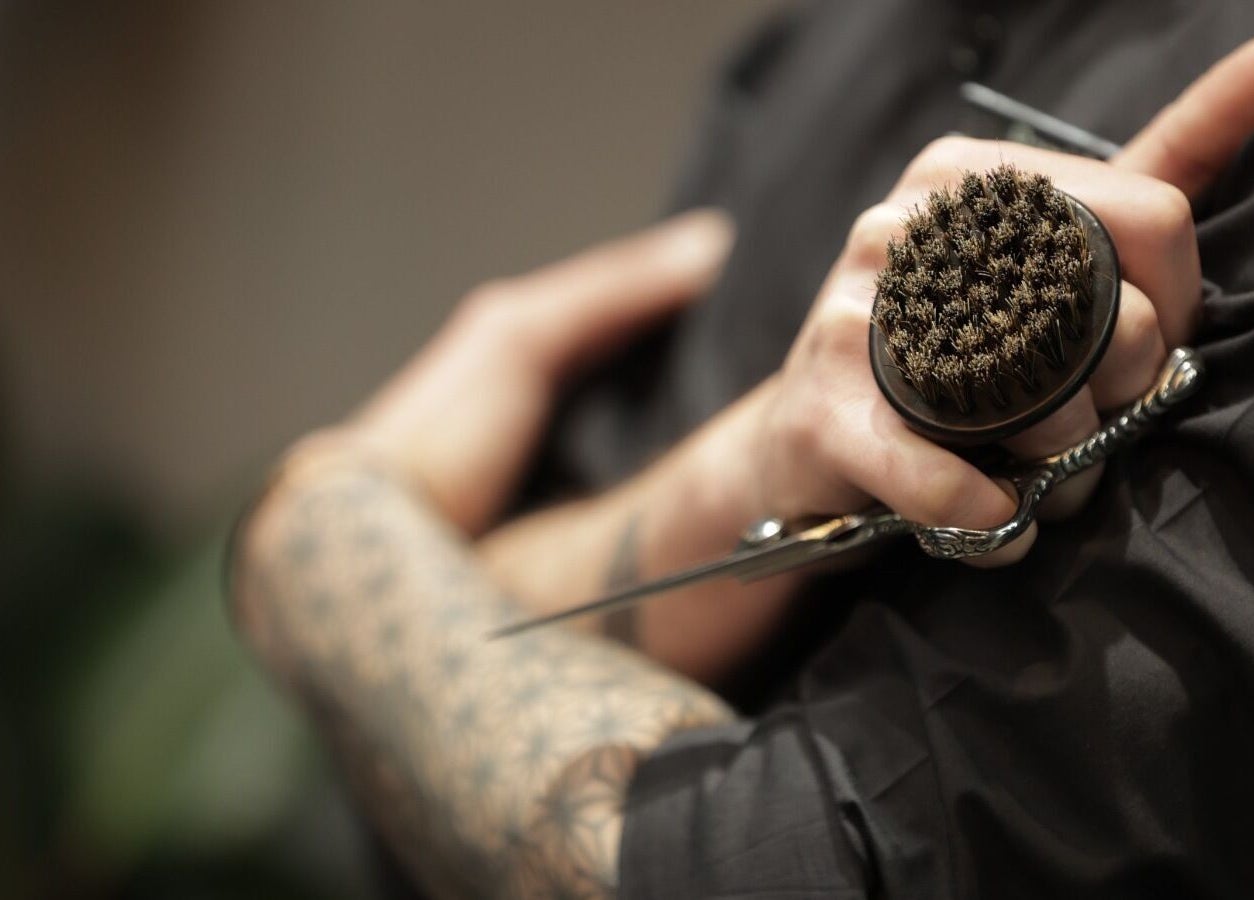 Close-up of barber holding brush and scissors at Cutz Hair Studio Premium, Riyadh, Riyadh Province, SA.