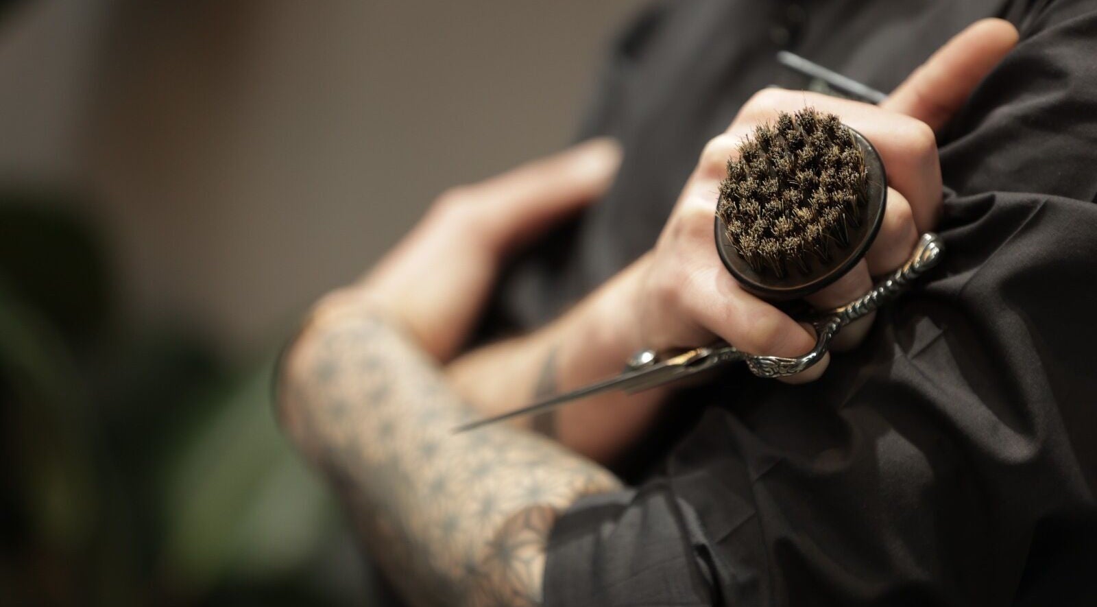 Close-up of barber holding brush and scissors at Cutz Hair Studio Premium, Riyadh, Riyadh Province, SA.