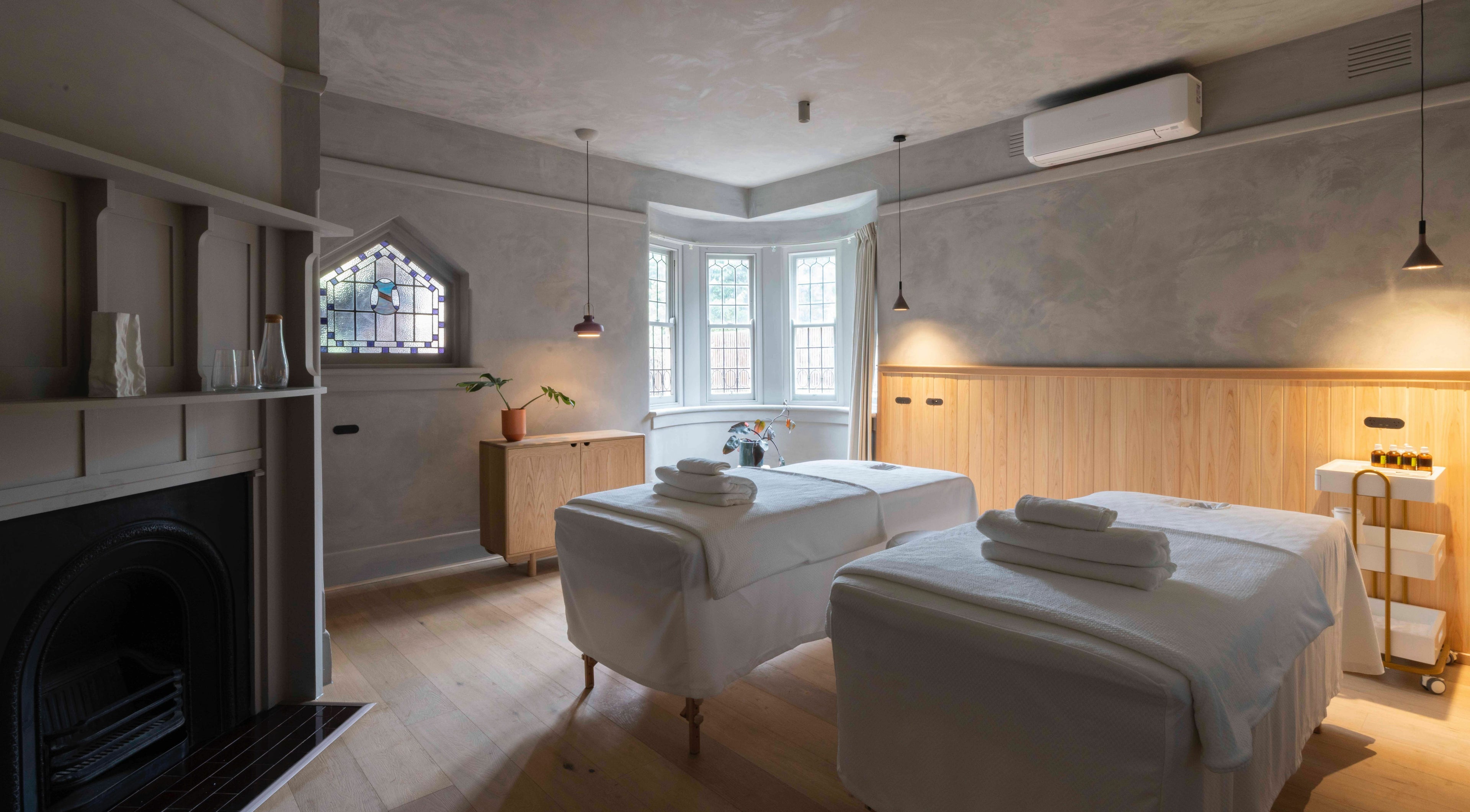 Relaxing massage room at In the Brick Spa, Melbourne, Victoria, AU, featuring twin beds and ambient lighting.