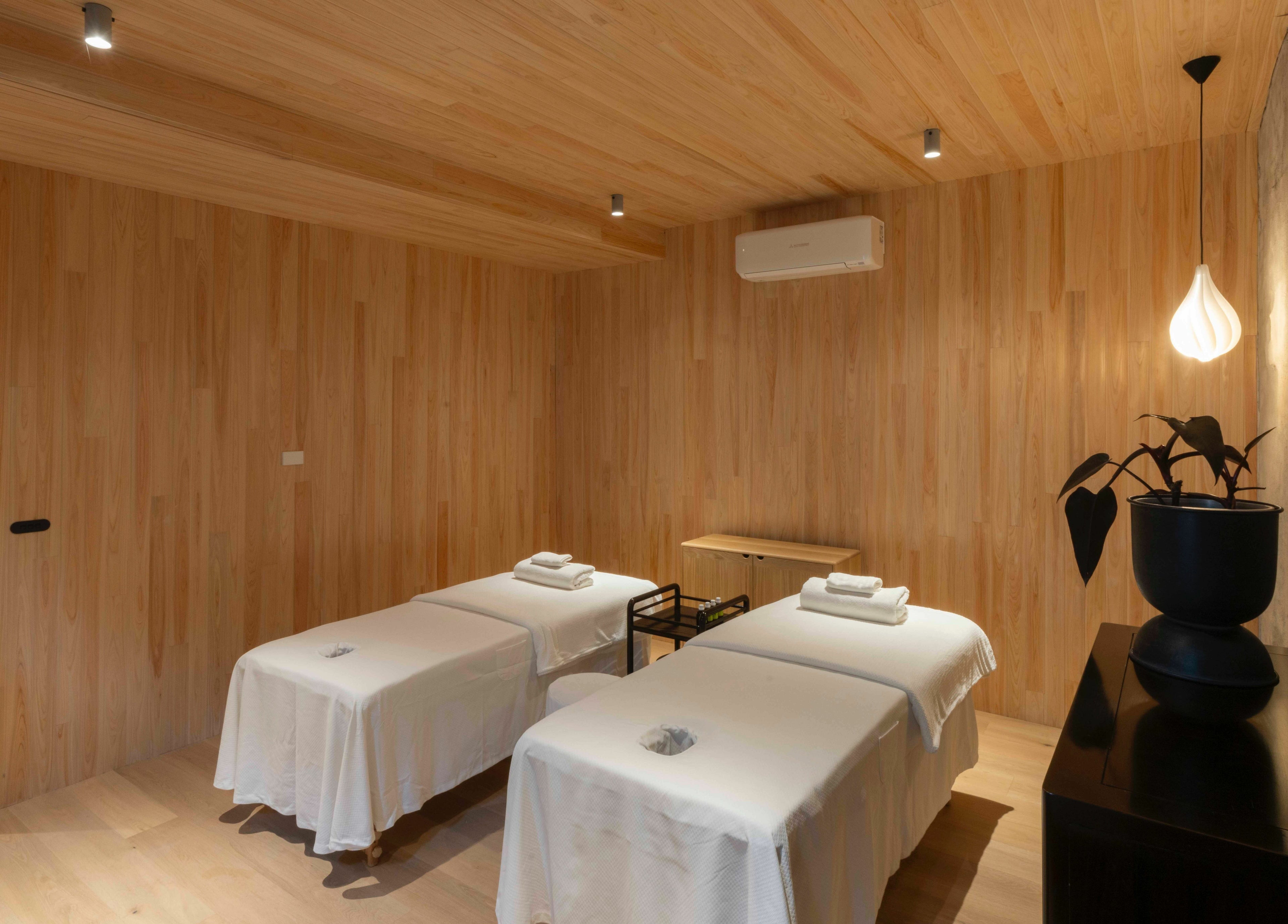 Relaxing massage room at In the Brick Spa, Melbourne, Victoria, AU with two beds under soft lighting.
