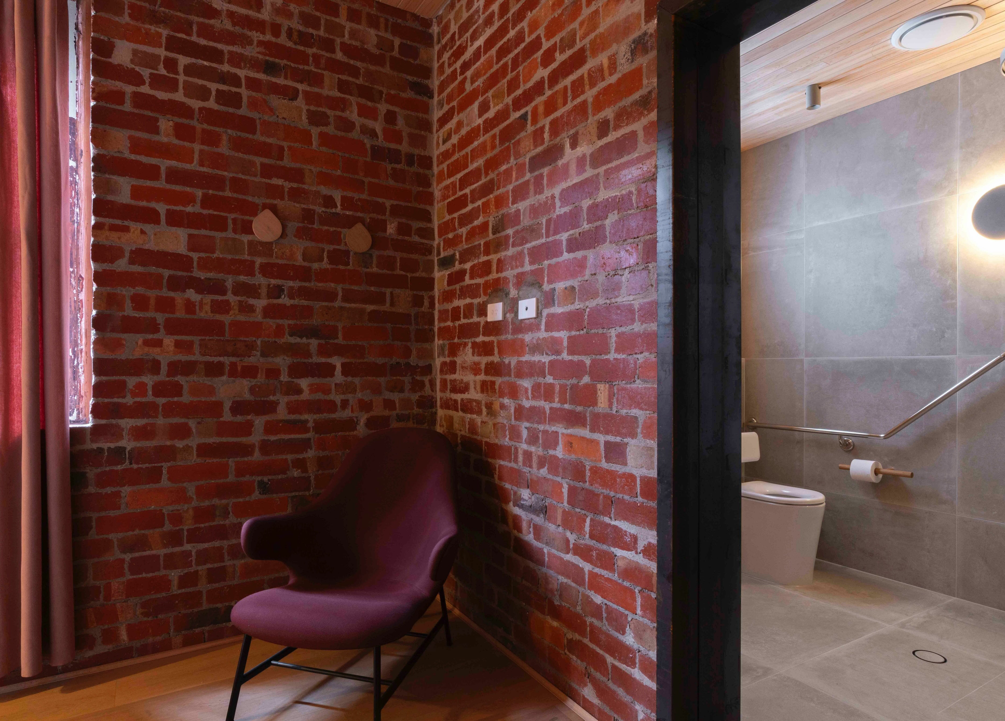 Cozy chair and rustic brick walls at In the Brick Spa, Melbourne, Victoria, AU, with modern bathroom access.