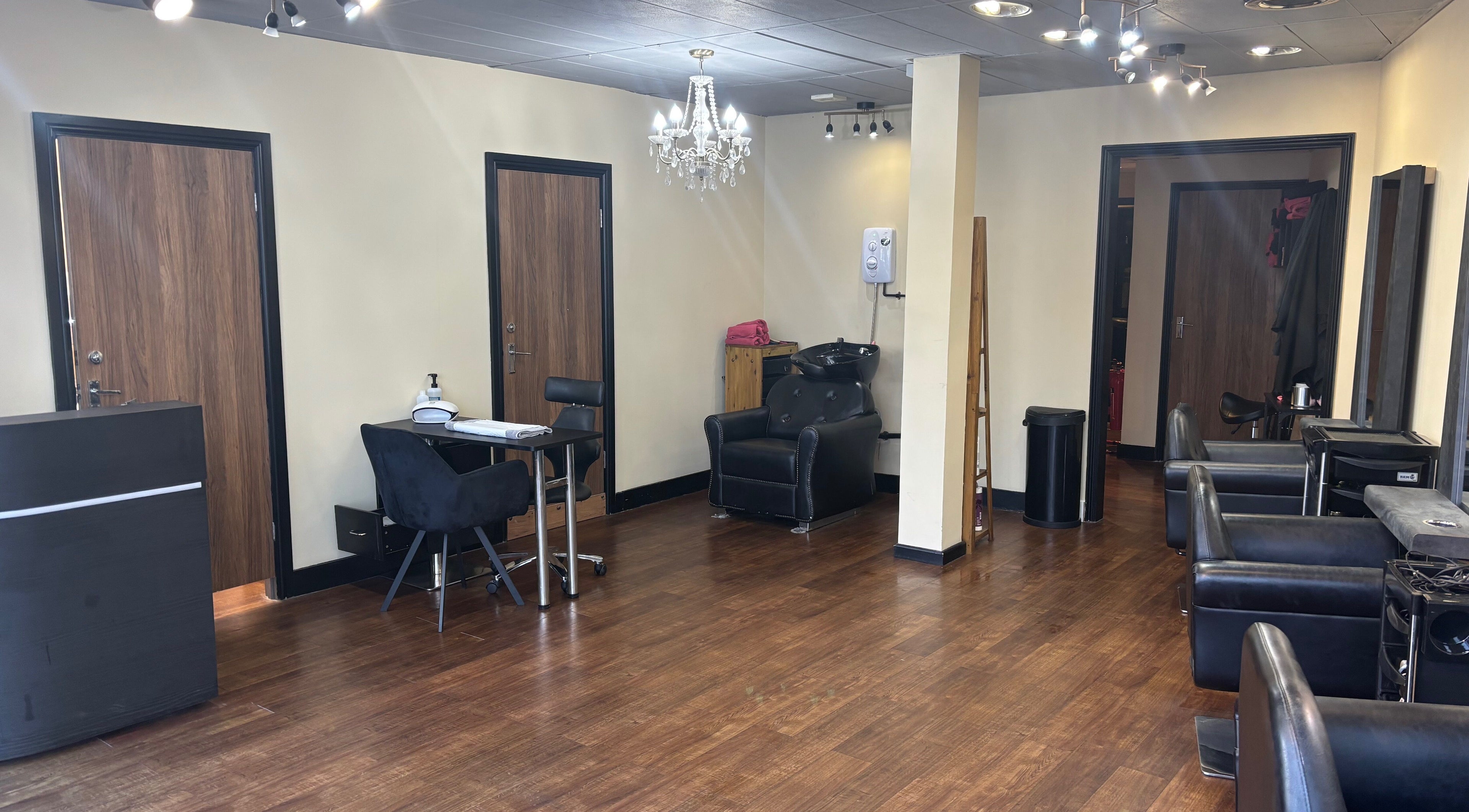 Spacious interior of Halo Hair and Beauty, Bristol, England, GB, featuring modern styling chairs and a chandelier.