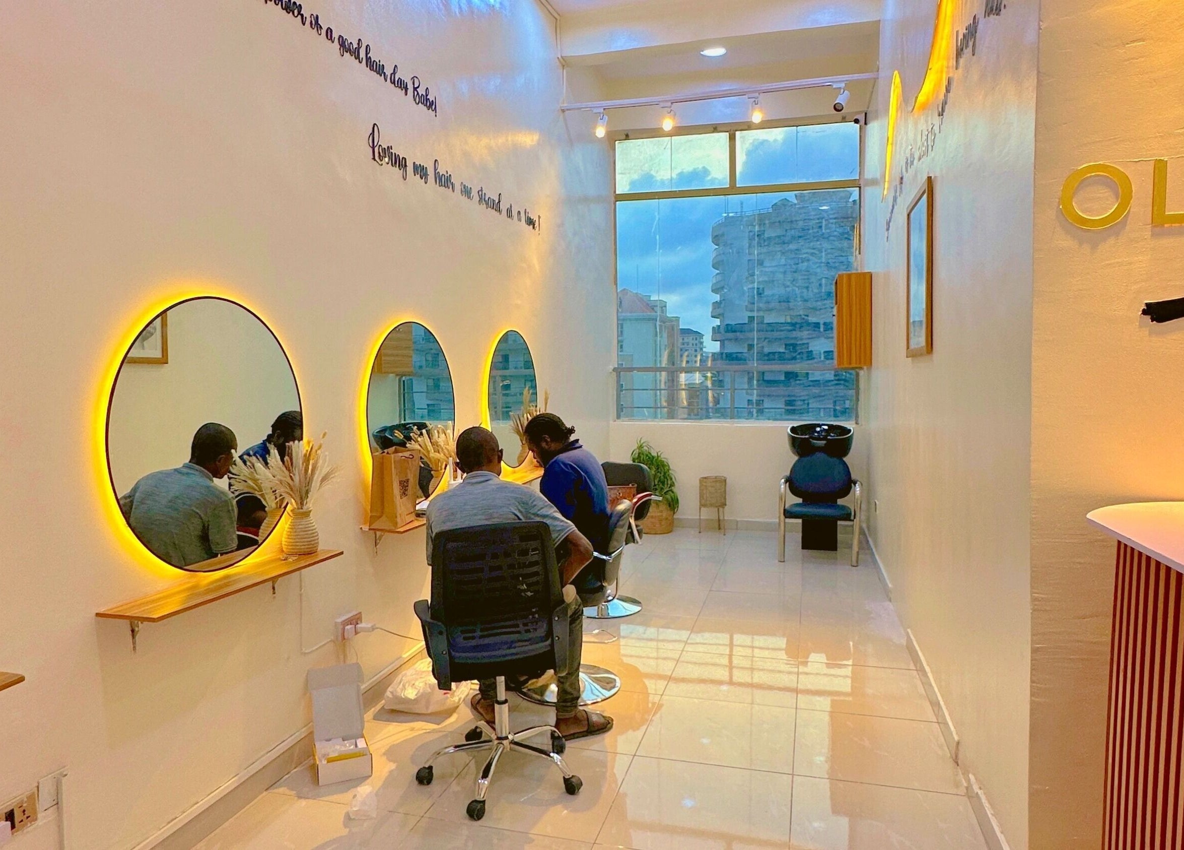 Stylish interior of O&Y Braiding Bar in Lagos, Lagos, NG with glowing mirrors and client chairs.