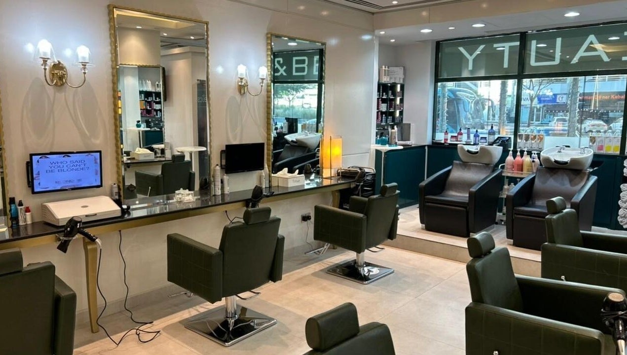 Modern interior of Osama Kasir Beauty Salon and Barbershop in Dubai, AE, featuring styling stations and washing chairs.