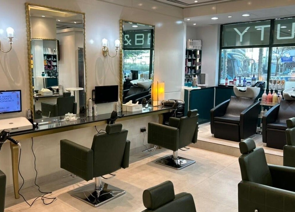 Modern interior of Osama Kasir Beauty Salon and Barbershop in Dubai, AE, featuring styling stations and washing chairs.