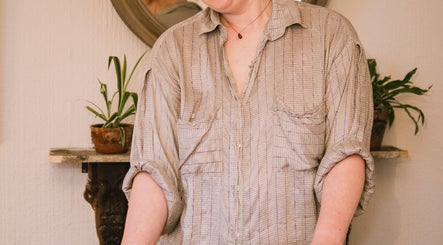 Therapist at Ruby's Refuge, Calstock, England, creating a calming atmosphere with plants and gentle expression.