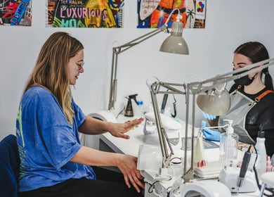 Client receiving manicure at Salon White Blue in Edmonton, Alberta, CA with colorful wall art in background.