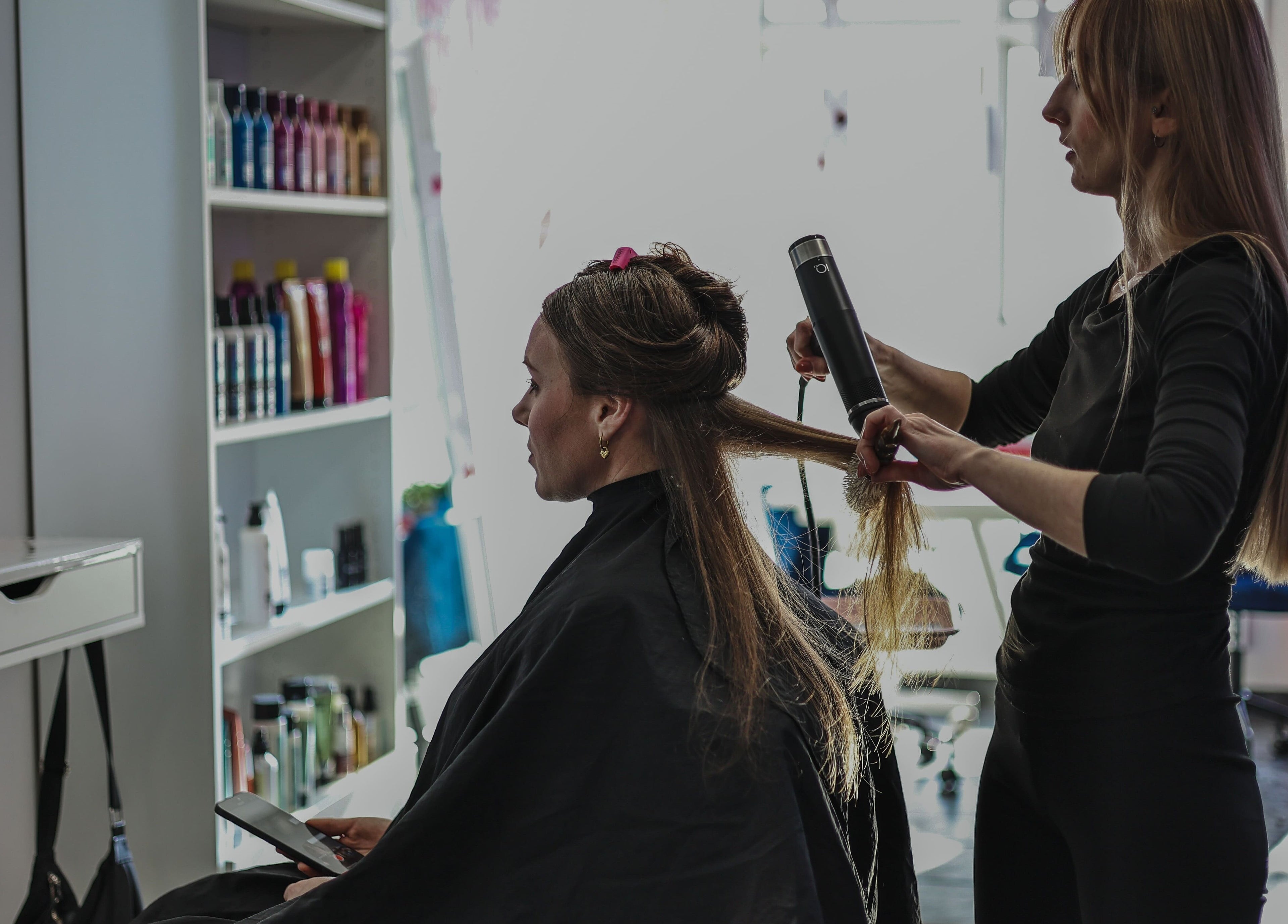Stylist straightening hair at Salon White Blue in Edmonton, Alberta, CA.